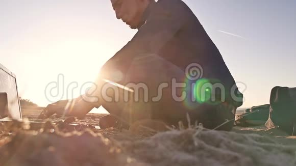 自由职业者一个在笔记本电脑上工作的人自由职业者坐在沙滩上夕阳阳光视频的预览图