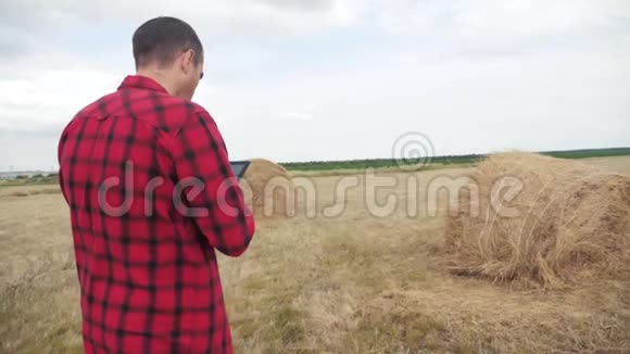 智慧农业理念一个农民在数字平板电脑上的田野里研究生活方式慢动作视频的预览图