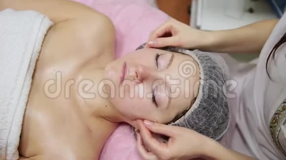 水疗女人面部按摩美容水疗沙龙面部按摩在美容水疗中心享受放松面部按摩的女性视频的预览图