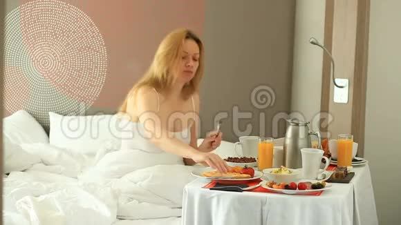 年轻女子在公寓的床上吃早餐视频的预览图