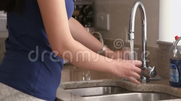 漂亮的年轻女人在厨房里喝水视频的预览图