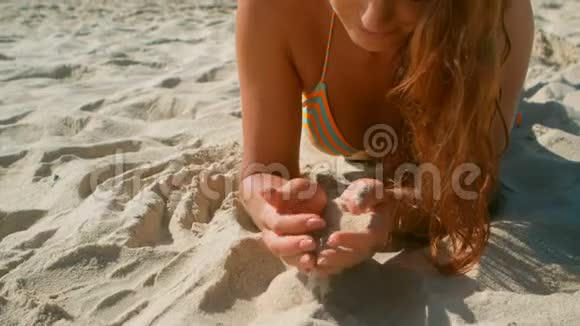 美丽的白种人年轻女士穿着比基尼在阳光下沙滩上放松视频的预览图