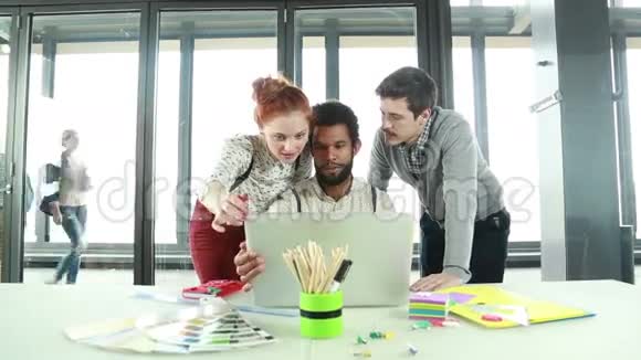 男性创意主管与同事讨论笔记本电脑的新创意视频的预览图