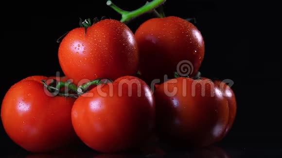 许多成熟的新鲜番茄躺在黑色的玻璃桌上绕着它的轴旋转特写新鲜蔬菜视频的预览图