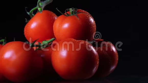 许多成熟的新鲜番茄躺在黑色的玻璃桌上绕着它的轴旋转特写新鲜蔬菜视频的预览图