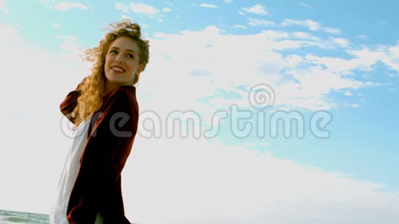 年轻的高加索女人站在阳光下的海滩上视频的预览图