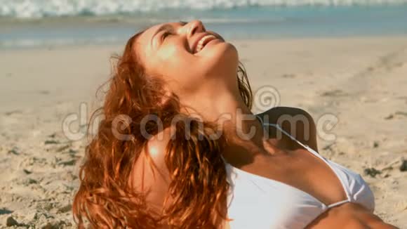 美丽的白种人年轻女士穿着比基尼在阳光下沙滩上放松视频的预览图