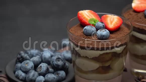 经典的提拉米苏甜点蓝莓和草莓在深色混凝土背景下的玻璃杯中视频的预览图