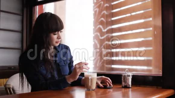 小女孩在咖啡馆里用智能手机视频的预览图