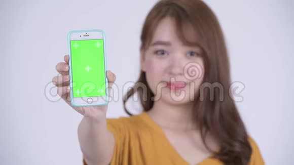 一位年轻快乐的亚洲女人展示电话视频的预览图