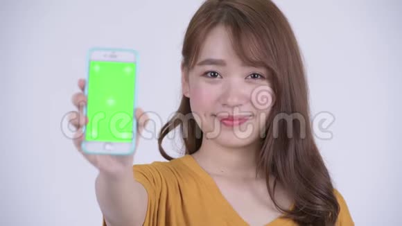 一位年轻快乐的亚洲女人展示电话视频的预览图