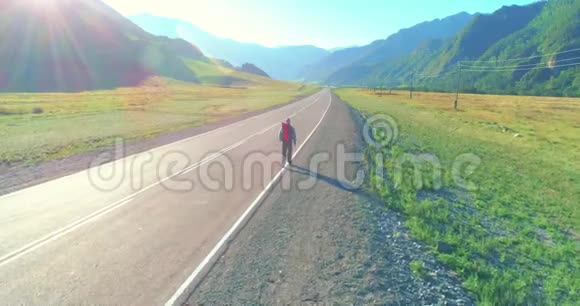 乘坐搭便车游客在沥青路上行走夏日的乡村山谷背包徒步旅行者视频的预览图