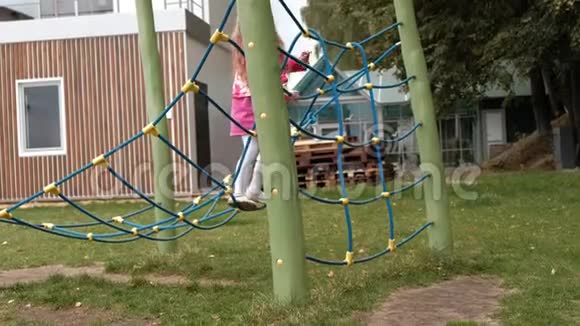 一个穿着粉红色裙子的小女孩和她的妈妈正在操场上玩一个绳梯视频的预览图