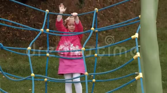 一个穿着粉红色裙子的小女孩和她的妈妈正在操场上玩一个绳梯视频的预览图