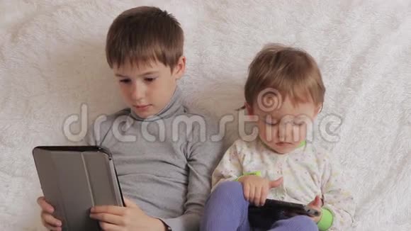 孩子们坐在沙发上玩你的平板电脑和电话视频的预览图