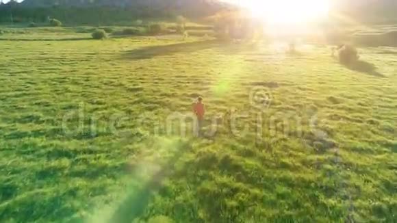 飞越运动男子跑在完美的绿色草地农村草地越野山上日落视频的预览图