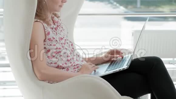 漂亮的女商人坐在玻璃办公室的白色椅子上在笔记本电脑后面工作视频的预览图