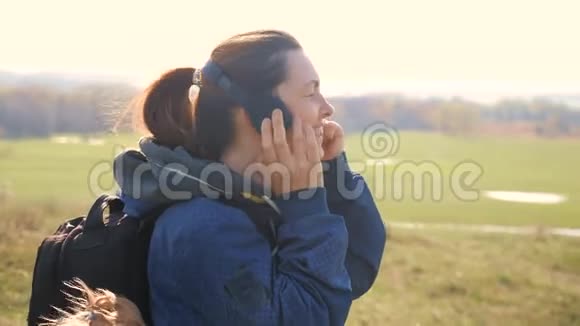 中年女性游客带着背包戴着耳机听着生活方式音乐看着智能手机视频的预览图