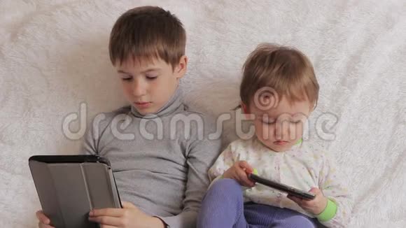 孩子们坐在沙发上玩你的平板电脑和电话视频的预览图