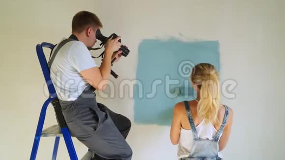 女工人用滚筒在水桶里粉刷公寓或房子里的墙壁建设修缮改造视频的预览图