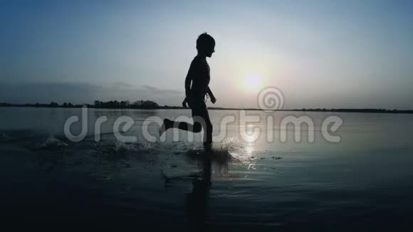日落时沿着海滩奔跑的快乐儿童剪影慢动作视频的预览图