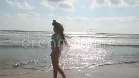 年轻漂亮的女孩在海边享受生活和乐趣穿着比基尼和衬衫在海滩上散步的快乐女人视频的预览图