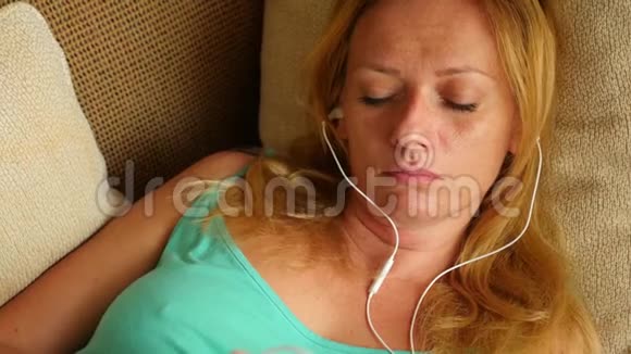 一天中睡在沙发上的人拿着电话里的耳机4k慢动作视频的预览图