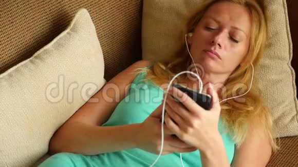 一天中睡在沙发上的人拿着电话里的耳机4k慢动作视频的预览图