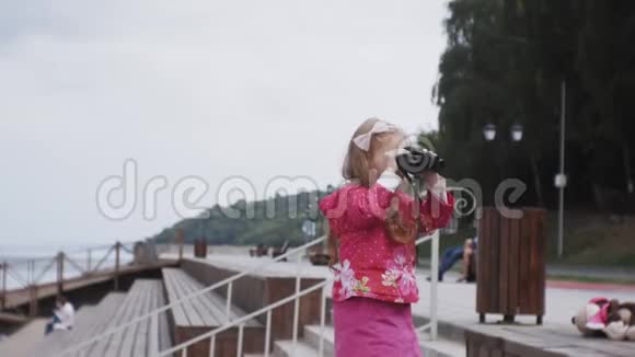 海滩上的小女孩用望远镜看视频的预览图