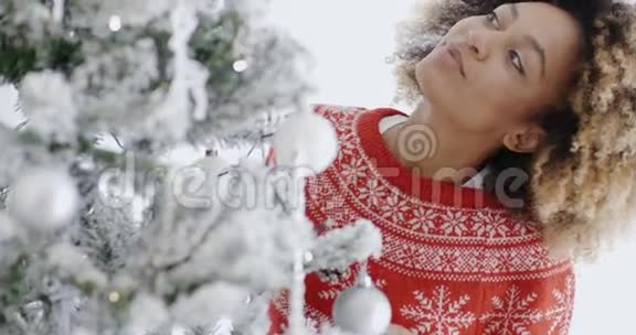 一个漂亮的年轻女人在装饰圣诞树视频的预览图