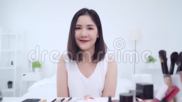 幸福美丽的年轻亚洲女人用化妆品评论化妆教程直播视频到社交网络视频的预览图