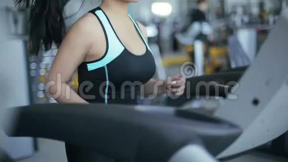 漂亮的亚洲女孩在健身房跑步机上跑步视频的预览图