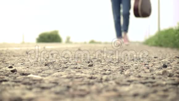 带着吉他的年轻女孩走在路上视频的预览图