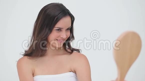 微笑的黑发女人拿着一面手镜视频的预览图
