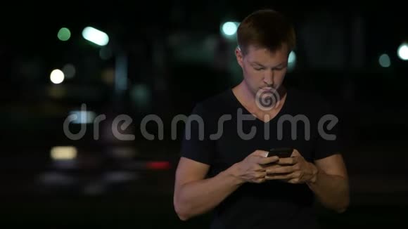 年轻英俊的斯堪的纳维亚人晚上在街上用电话视频的预览图