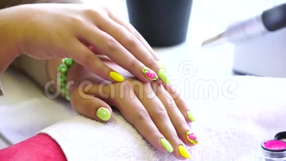 美容师在美甲沙龙中将指甲油涂在女性指甲上的特写镜头一只黄色的女人的手视频的预览图