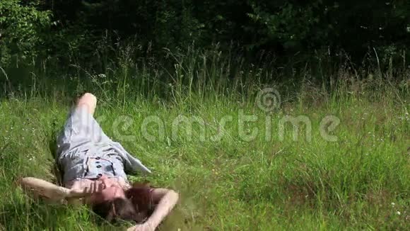 美丽快乐的女孩躺在草地上视频的预览图