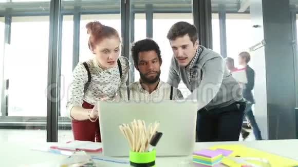 男性创意主管与同事讨论笔记本电脑的新创意视频的预览图