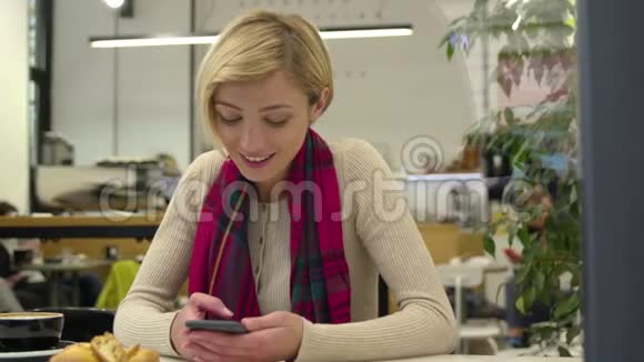 技术在室内咖啡厅使用手机的微笑女人视频的预览图
