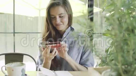 女人用信用卡在咖啡馆里用智能手机在线购物视频的预览图