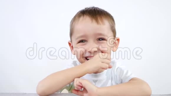 一个小孩坐在桌子旁的白色背景上的肖像视频的预览图