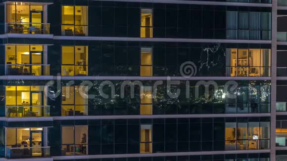 在玻璃摩天大楼的时间推移夜晚的公寓窗户会发光视频的预览图