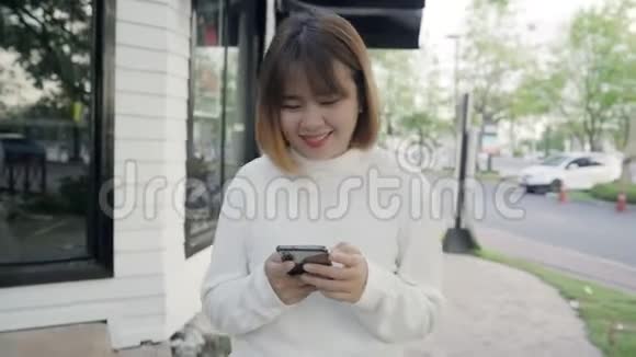 亚洲旅游博客女性晚上在市中心街头散步时在智能手机上使用触摸屏技术视频的预览图