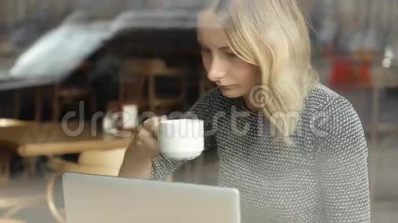 一位年轻漂亮的商务女士坐在一家有笔记本电脑的咖啡馆里视频的预览图