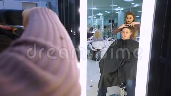 美容院的年轻帅哥那家伙坐在扶手椅上理发师剪了她的头发他就是视频的预览图
