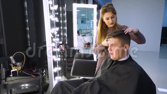 美容院的年轻帅哥那家伙坐在扶手椅上理发师剪了她的头发他就是视频的预览图