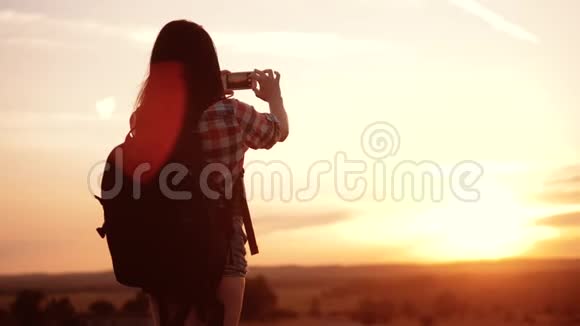 hipsterhiker剪影生活方式女孩正在手机智能手机上拍摄美丽自然日落的视频视频的预览图
