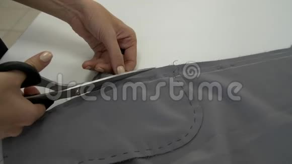 女性的双手用鞘把一块灰色的布割下来视频的预览图