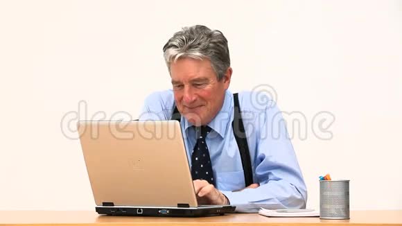 一个商人在他的笔记本电脑前微笑视频的预览图
