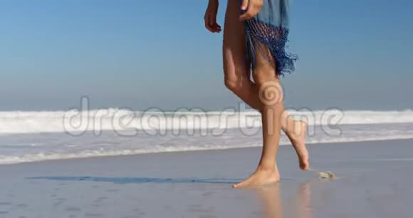 年轻女子在阳光下的海滩散步视频的预览图